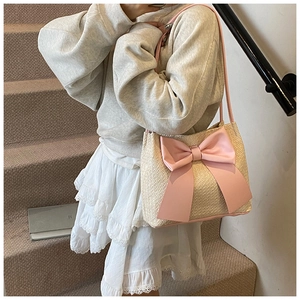 Détail du sac cabas en paille crème avec un grand nœud rose et des bandoulières roses
