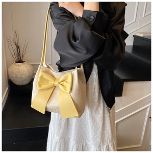 Détail du sac cabas en paille avec un grand nœud en soie jaune et fines bandoulières