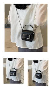 Close-up of mini black leather crossbody bag with silver bow buckle and chain strap
