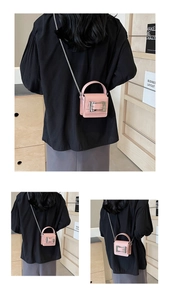 Rear view of a pink mini crossbody bag with silver chain strap on a black top