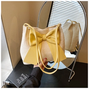 Détail d'un sac cabas en paille avec un grand nœud jaune et une texture tissée