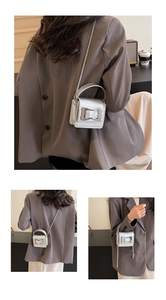 Detailed macro view of a silver metallic mini crossbody bag with a square buckle and chain
