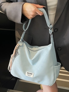 Minimalist light blue hobo tote bag with zipper closure and tassel detail for daily use