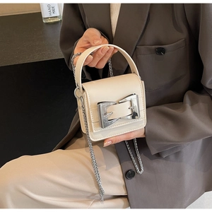 Detailed shot of cream mini crossbody bag featuring a large silver metal buckle and chain