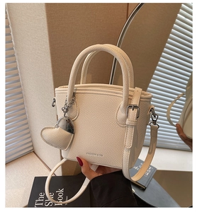 Detail view of cream lychee texture bucket bag with adjustable strap and heart charm