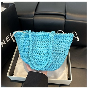 Detail of blue straw woven bucket bag with white drawstring closure and inner lining