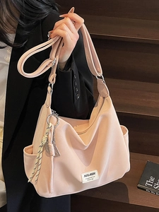 Pink canvas tote bag with adjustable strap and brand label shown in casual urban setting