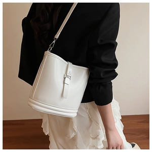 Détail d'un sac seau en cuir crème porté avec une tenue de bureau moderne et élégante
