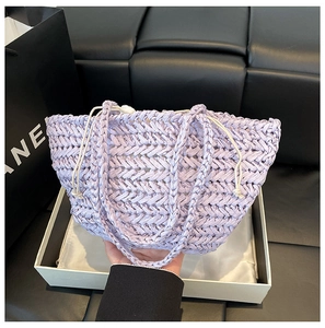 Close-up of purple woven straw tote with white drawstring closure and textured finish