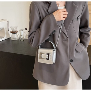 Detail shot of mini silver metallic crossbody bag with chunky square buckle and chain strap