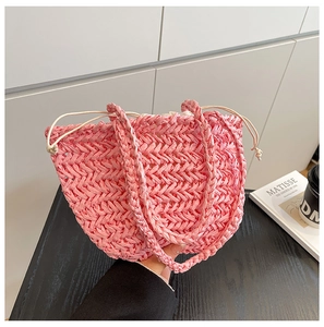 Close-up of pink straw woven tote bag featuring a drawstring closure and wavy weave pattern