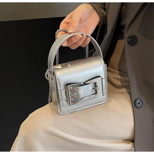 Close-up of metallic silver mini square bag with bold metal buckle and chain strap