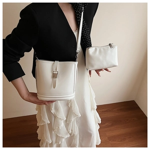 Gros plan d'un ensemble sac seau blanc avec boucle en métal porté par un mannequin
