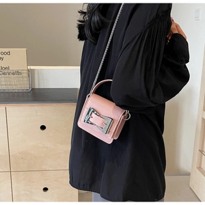 Detail of pink mini crossbody bag featuring a large silver buckle and slim chain strap