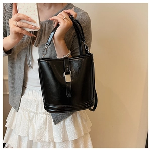Détail d'un sac seau noir brillant avec boucle en métal argenté et texture plissée