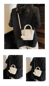 Detail of white lychee pattern leather bucket bag with heart pendant and crossbody strap