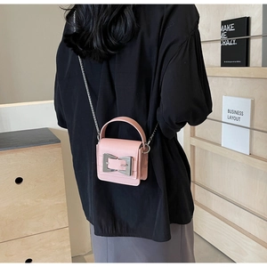 Detail of pink mini bag with silver bow buckle and chain strap on a black shirt