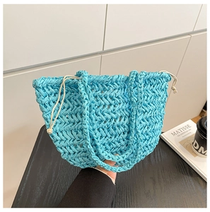 Close-up of bright light blue hand-woven straw tote bag with intricate herringbone pattern