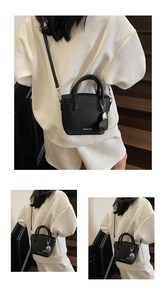 Detail of black lychee texture bucket bag featuring heart charm and fashion lettering