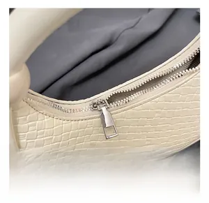 Detail showing the silver metal zipper and woven texture of the cream dumpling handbag