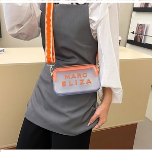 Détail du sac à bandoulière transparent avec sangle orange en zigzag et logo MARC ELIZA