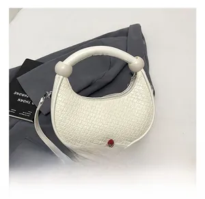Macro shot of white crocodile embossed leather bag with round ball handle and metal buckle