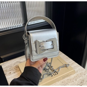 Detail of a silver mirror mini crossbody bag with a large metallic buckle and chain strap