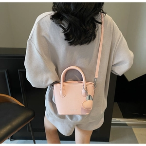 Pink lychee grain bucket bag with heart charm shown on model from a back perspective