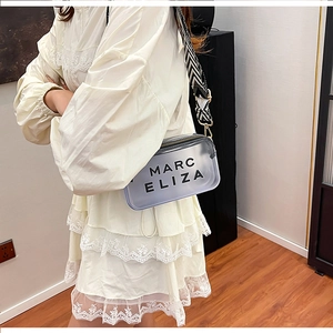 Détail du sac à bandoulière gris transparent avec lettres noires et sangle à chevrons