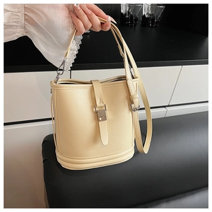 Détail du sac seau crème montrant la texture du cuir PU et le fermoir en métal chic