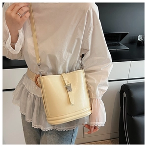 Vue détaillée d'un sac seau crème montrant le cuir texturé et la boucle métallique