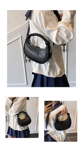 Close-up of black woven leather crescent handbag with elegant ball charms and crossbody strap