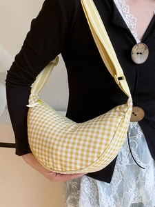Borsa a mezzaluna a quadretti gialli con tracolla larga regolabile indossata da modella