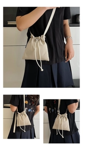 Detail of a minimalist off-white drawstring bucket bag with soft pleated nylon texture