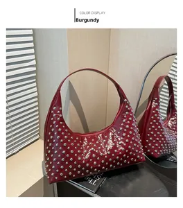 Detailansicht einer weinroten Lackleder-Achseltasche mit silbernen Nieten-Verzierungen