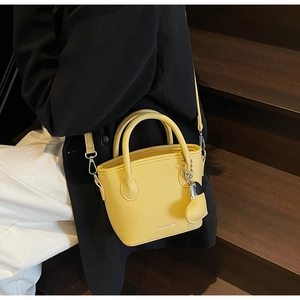 Detail of yellow lychee pattern bucket bag with heart pendant and fashion text