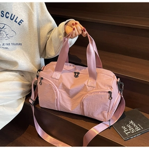 Pink nylon fitness bag with dual handles and shoe compartment on dark wood stairs
