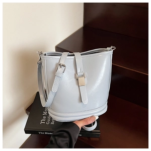 Gros plan du sac seau bleu clair en cuir verni avec boucle argentée sur escaliers