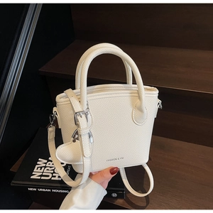 Detail view of white lychee leather bucket bag with heart charm and fashion lettering