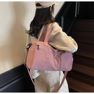 Pink waterproof nylon gym bag with multiple pockets shown worn by a model on stairs
