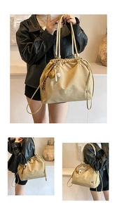 Detail of light brown pleated shoulder bag with drawstring and baseball charm accessory