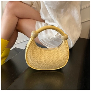 Detail of yellow crocodile pattern handbag with spherical hardware and arched handle