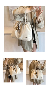 Detail of cream canvas drawstring tote bag with elegant tassel and metal logo accent