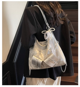 Detail of silver metallic hobo bag featuring rivet belts, pearl bow, and lace charms