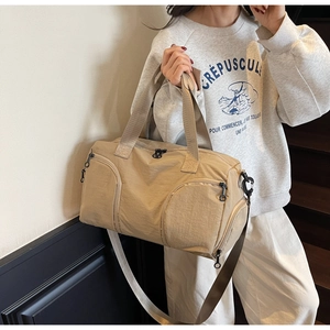 Detail view of khaki travel bag showing multiple zippers and water-resistant nylon texture