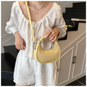 Detail of yellow woven leather hobo bag with translucent handle on a white outfit