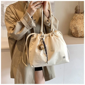 Detail of cream white drawstring tote bag with heart pendant on a neutral background