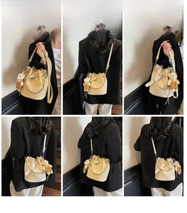 Beigefarbene Beuteltasche mit Litschi-Struktur und Metallkette an einem Model im Gitter