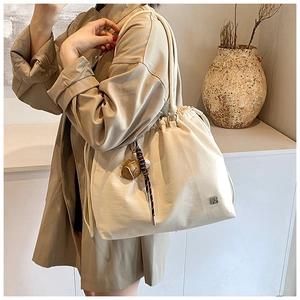 Detail of cream large-capacity bucket bag with drawstring closure and rugby charm