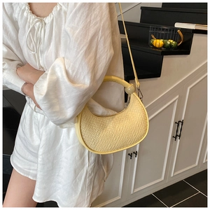 Detail of yellow woven hobo bag with crocodile texture and unique round handle